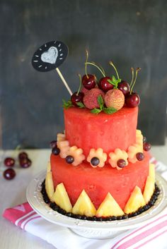 a watermelon cake with cherries and strawberries on top