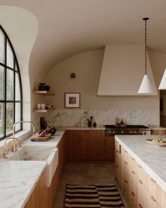 a large kitchen with marble counter tops and wooden cabinetry, along with an arched window