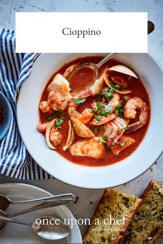 a bowl of soup with shrimp and bread on the side