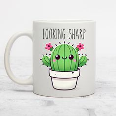 a white coffee mug with a green cactus in it's pot that says looking sharp