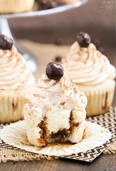 two cupcakes with white frosting and chocolate on top, sitting on a napkin