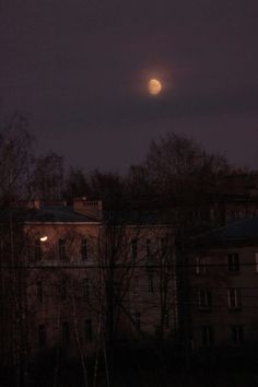 the full moon is seen over an old building