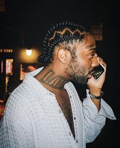 a man with dreadlocks on his head talking on a cell phone while wearing a white shirt