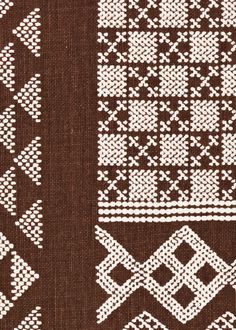 some white and brown knitted designs on fabric, including one with an arrow in the middle