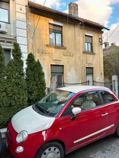 a red and white car parked in front of a building