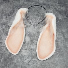 a pair of pink and white furry shoes on a gray surface with wires in the middle