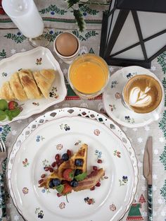 a table topped with plates and cups filled with breakfast food next to an orange juice