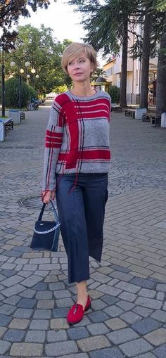 a woman is walking down the street with her hand in her pocket and wearing red shoes