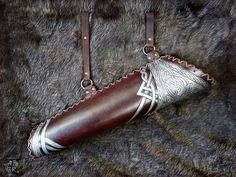 a brown leather case with silver designs on the handle and straps hanging from it's sides