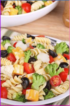 a plate full of pasta salad with broccoli and tomatoes on the side,