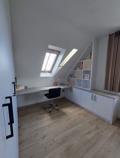 an empty room with a desk, shelves and window in the corner on the wall