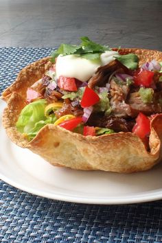 a taco filled with meat, lettuce and tomatoes on a white plate