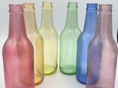 six different colored glass bottles lined up in a row