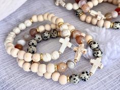 three different bracelets with beads and cross charms on top of each beaded one