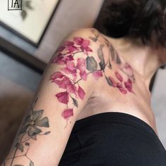 a woman's arm with flowers on it and the back of her body covered in tattoos