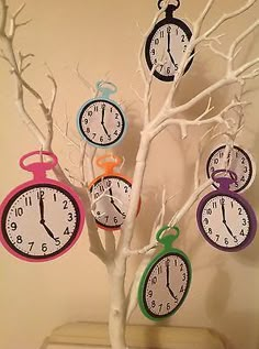 a tree with clocks hanging from it's branches in front of a white wall