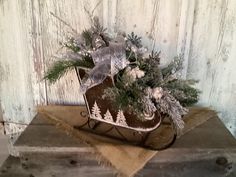 a sleigh filled with evergreens and pine cones on top of a table