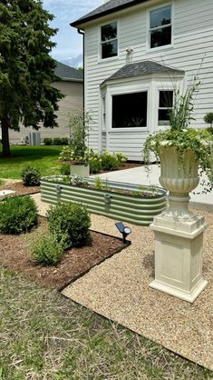 a large white vase sitting on top of a cement bench in front of a house