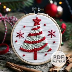 a white and red christmas tree on a wooden hoop with cinnamon sticks next to it