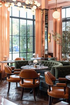 a restaurant with tables, chairs and couches in front of large windows that look out onto the street