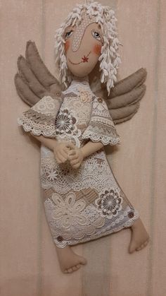 an angel doll with white hair and brown eyes is posed on a beige striped background