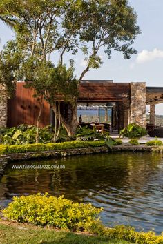 a house sitting on top of a lush green hillside next to a lake and forest