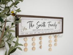 a family name sign hanging on the wall next to a potted plant with leaves