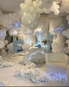 a room filled with balloons and white furniture next to a wall covered in snowflakes