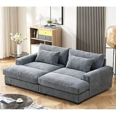 a living room scene with focus on the grey couch and wooden floor, along with an end table