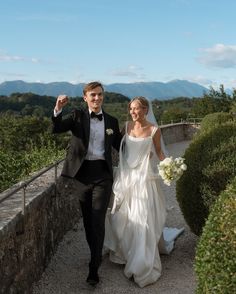 a bride and groom walking down a path