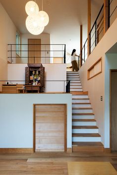 there is a woman walking up the stairs in this modern house with wood floors and white walls