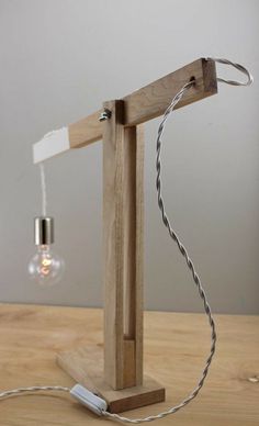 a wooden table lamp with an electric cord attached to the light bulb and plugged in