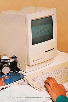 an old computer sitting on top of a desk next to a camera and other items