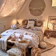 a bedroom decorated in white with lights on the ceiling and blankets, pillows, rugs and other decorations