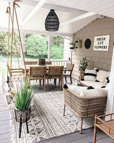 the porch is decorated with wicker furniture and hanging plants on the side of the house