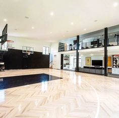 an indoor basketball court with hard wood flooring and white walls in the middle of it