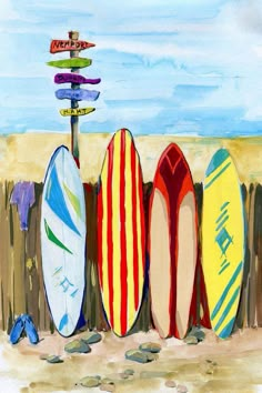 four surfboards are lined up against a wooden fence on the beach with signs pointing in different directions