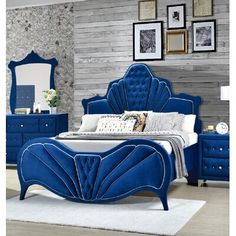 a blue bed sitting in front of a mirror on top of a wooden dresser next to a white rug