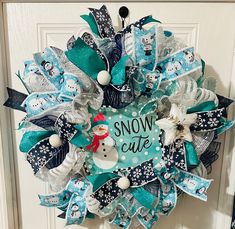 a snowman wreath hanging on the front door with words written in black, white and blue