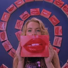 a woman holding up a piece of red paper with her mouth open and lips painted on it