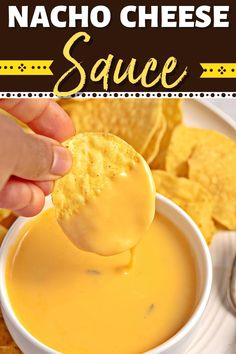 a hand holding a cracker over a bowl of nacho cheese sauce