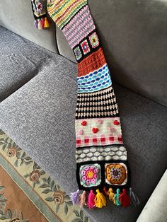 a multicolored crocheted scarf laying on the back of a gray couch