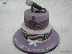 a birthday cake with a microphone on top and music notes on the side, sitting on a white tablecloth