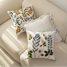 three pillows sitting on top of a white couch