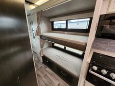 the interior of a travel trailer with bunk beds and stove top ovens in it