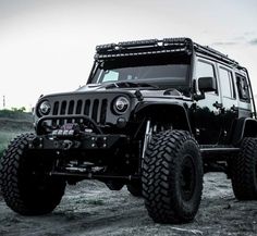 a black jeep parked on top of a dirt field