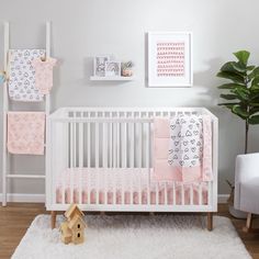 a white crib with pink and gray bedding in a nursery room next to a chair