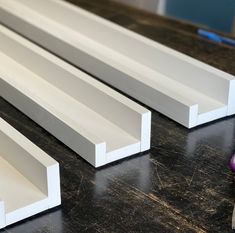 three white frames sitting on top of a wooden table next to a purple ball and pencil