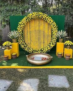 a yellow and green backdrop with flowers on the ground, vases and candles in front of it