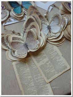 several butterflies are sitting on top of an open book with pages cut out to look like books